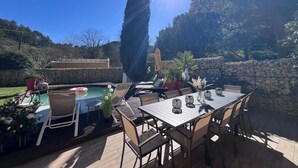 An outdoor patio with a pool, dining table, chairs, and potted plants. - Maison idéale pour les familles avec piscine privée - Fontaine-de-Vaucluse (Fontaine-de-Vaucluse)
