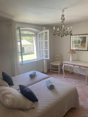 Un dormitorio con dos camas, un escritorio, una silla y una ventana con cortinas.