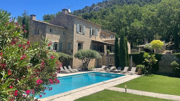 A stone villa with a swimming pool, surrounded by lush greenery and a mountainous backdrop. - Propriété d'exception au coeur du Luberon (Robion)