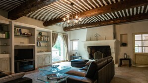 A spacious living room with a fireplace, leather sofa, glass coffee table, and bookshelves. - Propriété d'exception au coeur du Luberon (Robion)