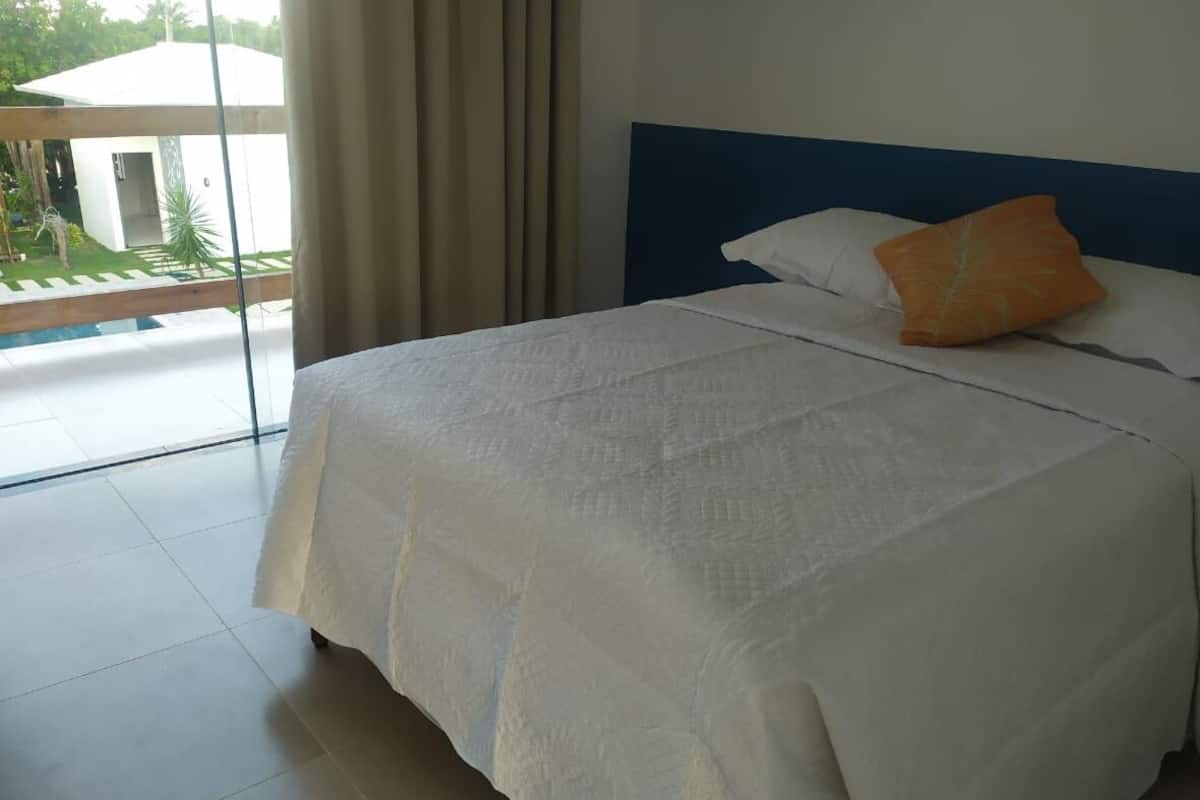 A hotel room with a large bed, a view of a garden, and a balcony.