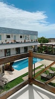 Una casa moderna con piscina, terraza de madera y mobiliario exterior.