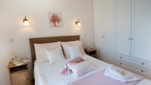 A neatly made bed with pillows and a blanket, a bedside table with a lamp, a nightstand with a book and a lamp, and a wardrobe with doors. - Villa Pasithea - breathtaking seaviews, infinity pool, privacy, close to beach (Perigiali)