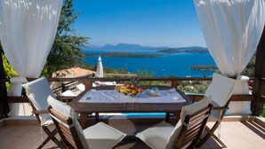 A terrace with a table set for two, overlooking a scenic view of the sea and hills. - Villa Pasithea - breathtaking seaviews, infinity pool, privacy, close to beach (Perigiali)