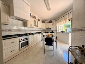 A modern kitchen with white cabinetry, a gas stove, and a dining area with a table set for breakfast.
