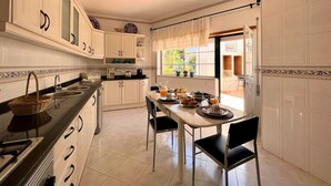 A kitchen with white cabinets, a dining table with chairs, and a window with curtains. - LAGOS TYPICAL HOUSE by HOMING (Lagos)