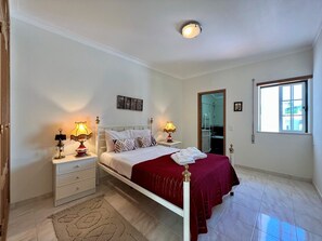 A bedroom with a bed, nightstands, a mirror, and a window.