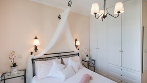Een netjes ingerichte slaapkamer met een hemelbed, nachtkastjes met lampen, een garderobe en een kroonluchter.