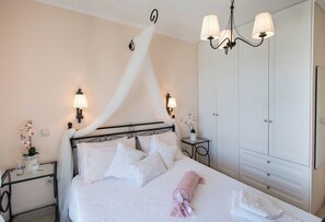 Quarto bem organizado com cama de dossel, mesas de cabeceira com luminárias, guarda-roupa e um candelabro.
