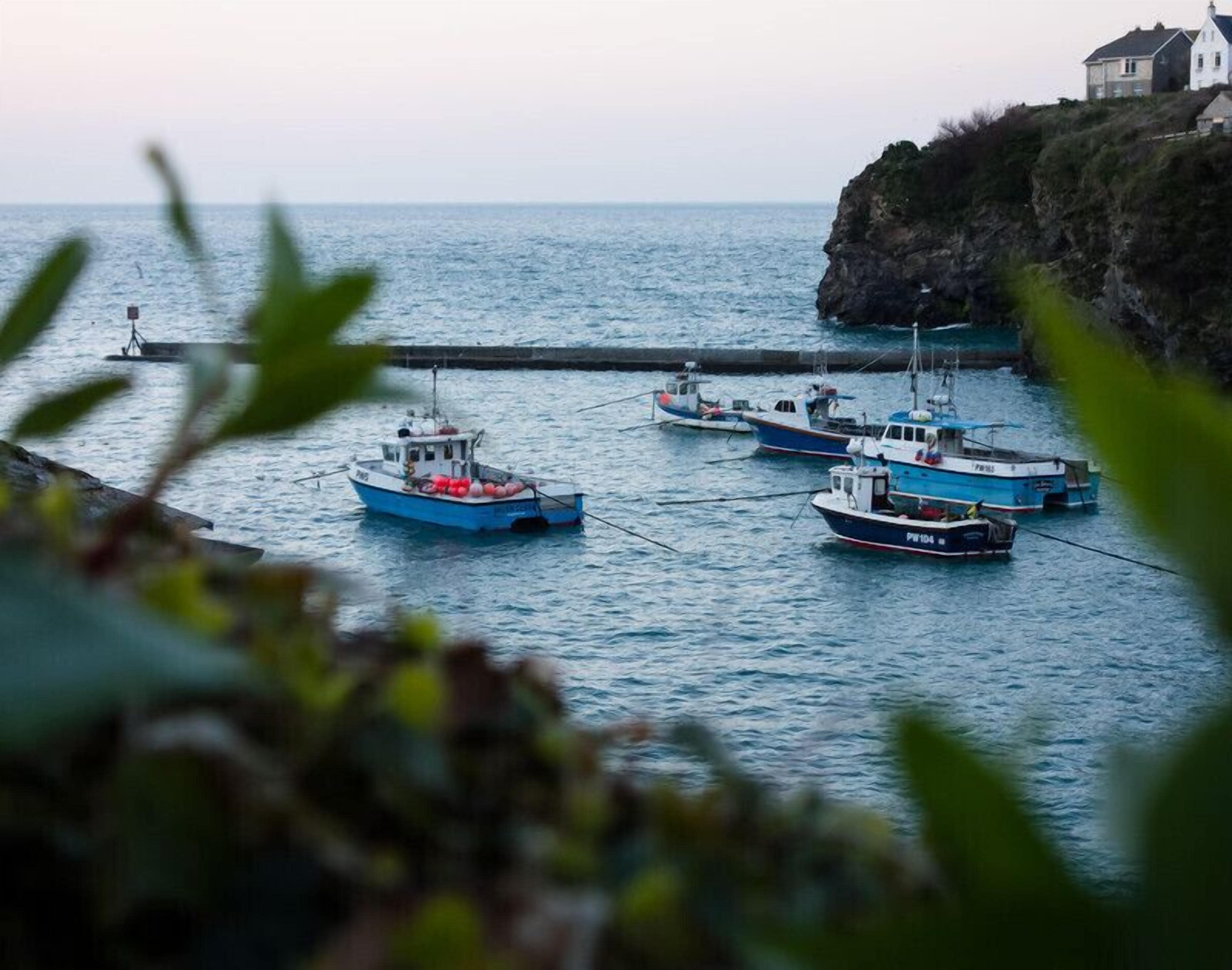 A harbor with several boats docked near a rocky coastline.