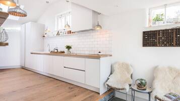 Une cuisine moderne avec des meubles blancs, un plan de travail en bois et des luminaires suspendus.