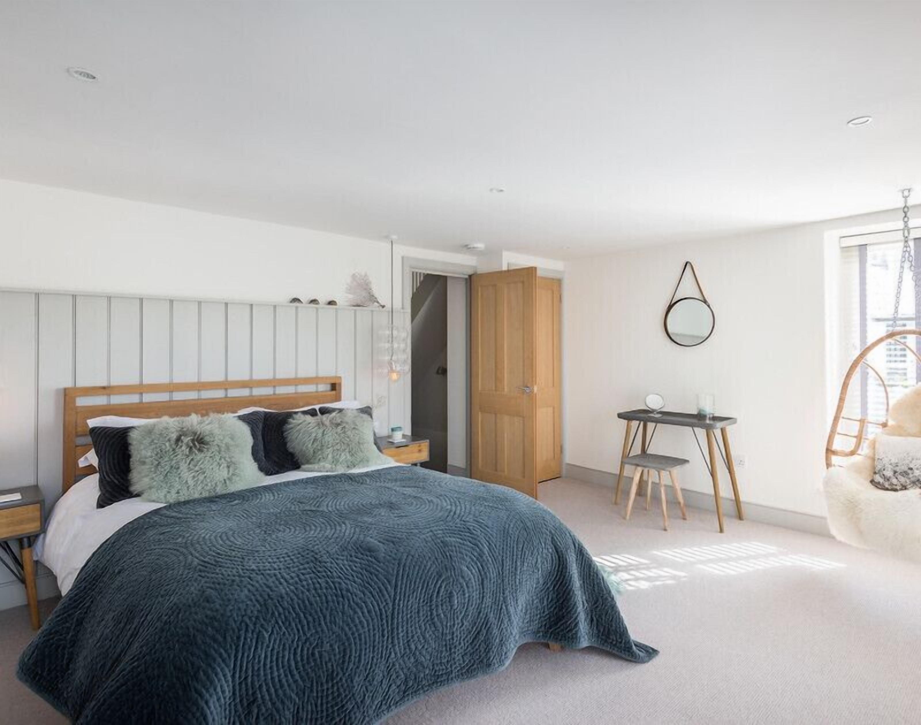 Ein Schlafzimmer mit einem Bett, Nachttischen, einem Schreibtisch, einem Stuhl und einem Kleiderschrank.