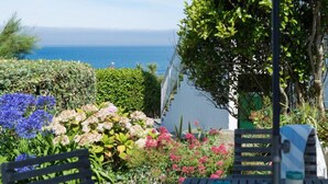 A garden with a bench and table, a view of the sea, and a tree. - Albany (Port Isaac)