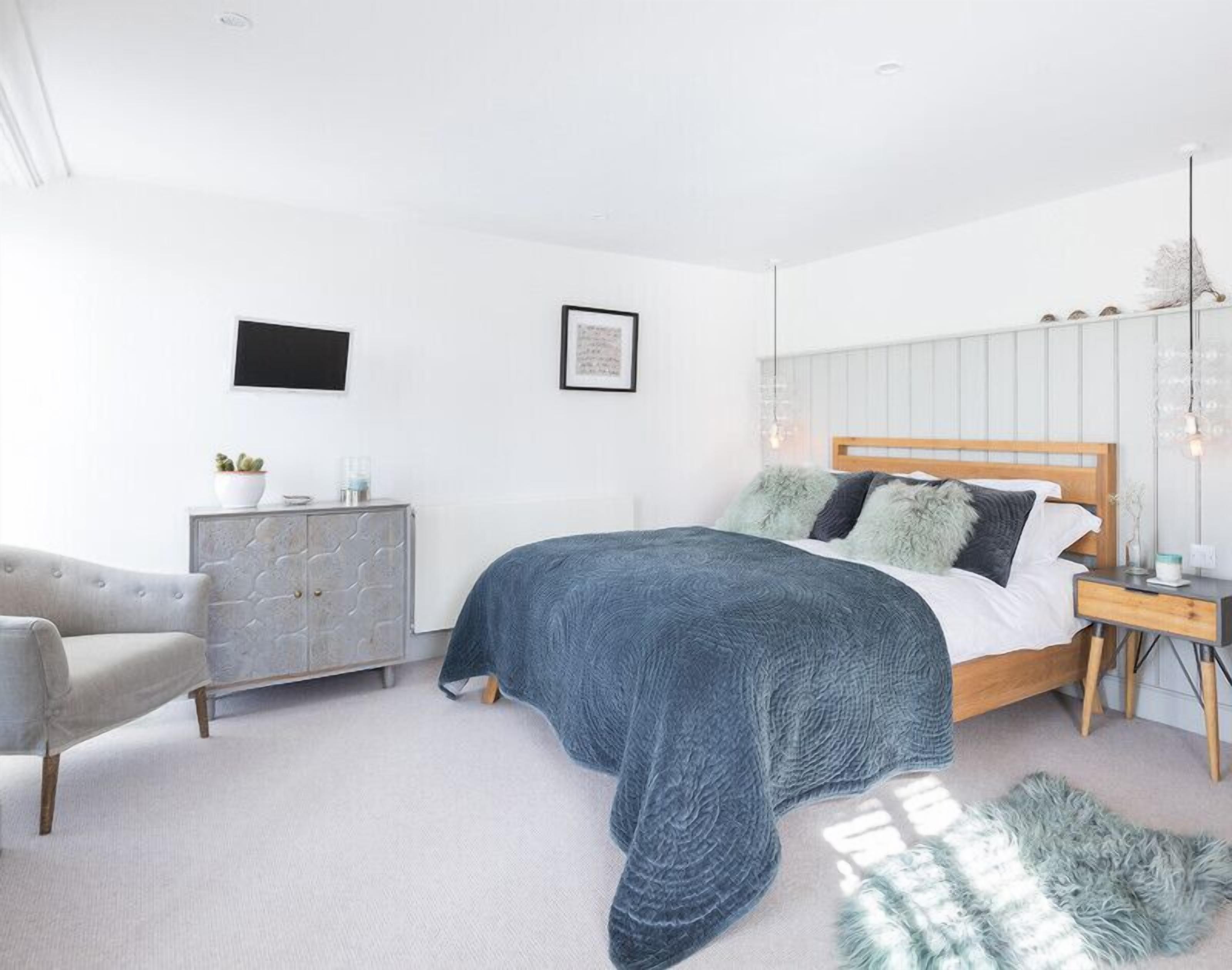 A bedroom with a bed, a dresser, a chair, and a bedside table.