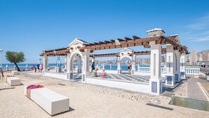 Een boulevard aan zee met een pergola, zitgedeeltes en uitzicht op de zee.