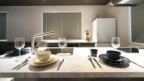 Una cucina moderna con zona pranzo apparecchiata per due persone, che include un rubinetto in acciaio inossidabile, due bicchieri da vino, una ciotola e un coltello sul tavolo.