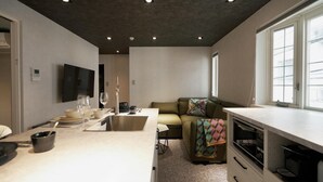 Una cucina moderna con zona pranzo, divano e TV a parete.
