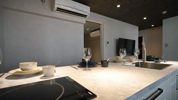 Una cucina moderna con forno integrato, lavello e un piano di lavoro con diversi utensili da cucina.