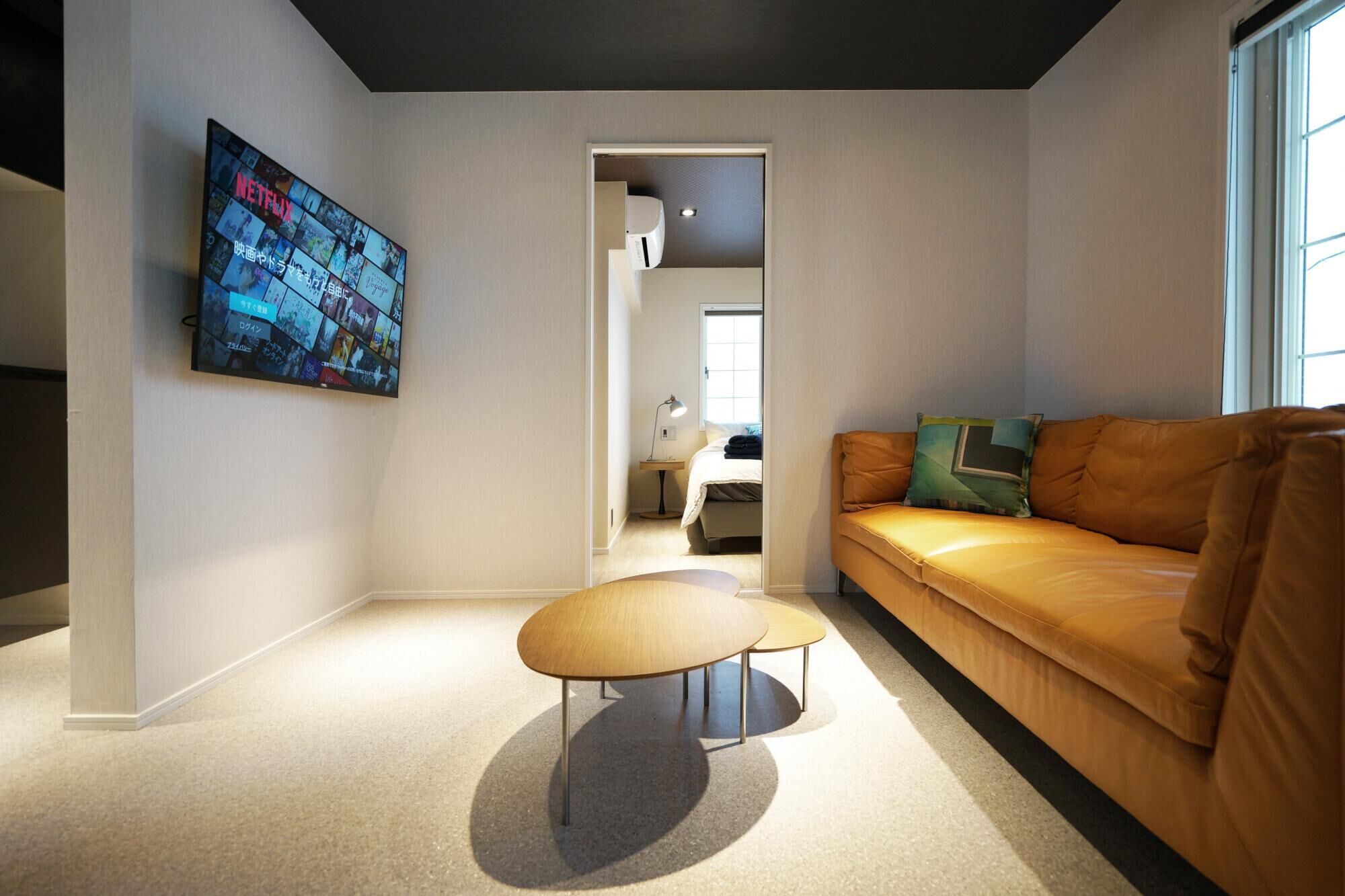 A modern living room with a leather sofa, a coffee table, and a wall-mounted TV displaying Netflix content.