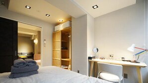 Une chambre d’hôtel comprenant un lit, un bureau avec une chaise, une armoire et un miroir.