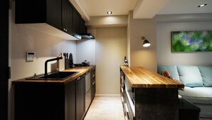 A modern kitchen with dark cabinetry, a wooden countertop, and a built-in oven. - Real Life Kudanshita Posh 1-bedroom 5pax 3mins sub (Tokyo)