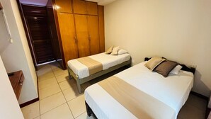 A bedroom with two beds, a wardrobe, and a small table. - Buongiorno Suites Sullana I (Sullana)