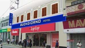 A hotel named Buongiorno Hotel with a red and blue facade, a visible storefront with a 'topshop' sign, and a 'Bata' sign nearby. - Buongiorno Suites Sullana I (Sullana)