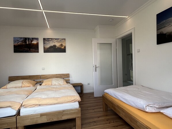 A bedroom with a wooden bed, a smaller single bed, and two paintings on the wall. - SUNRISE with large terrace and far-reaching views (Pirmasens-Erlenbrunn)