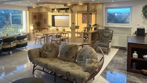 A modern living room with a dining area, a sofa with floral upholstery, and a view of the outdoors through large windows.
