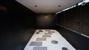 Un pasillo con un camino alfombrado que lleva a una habitación, un letrero en la pared y una ventana con persianas.