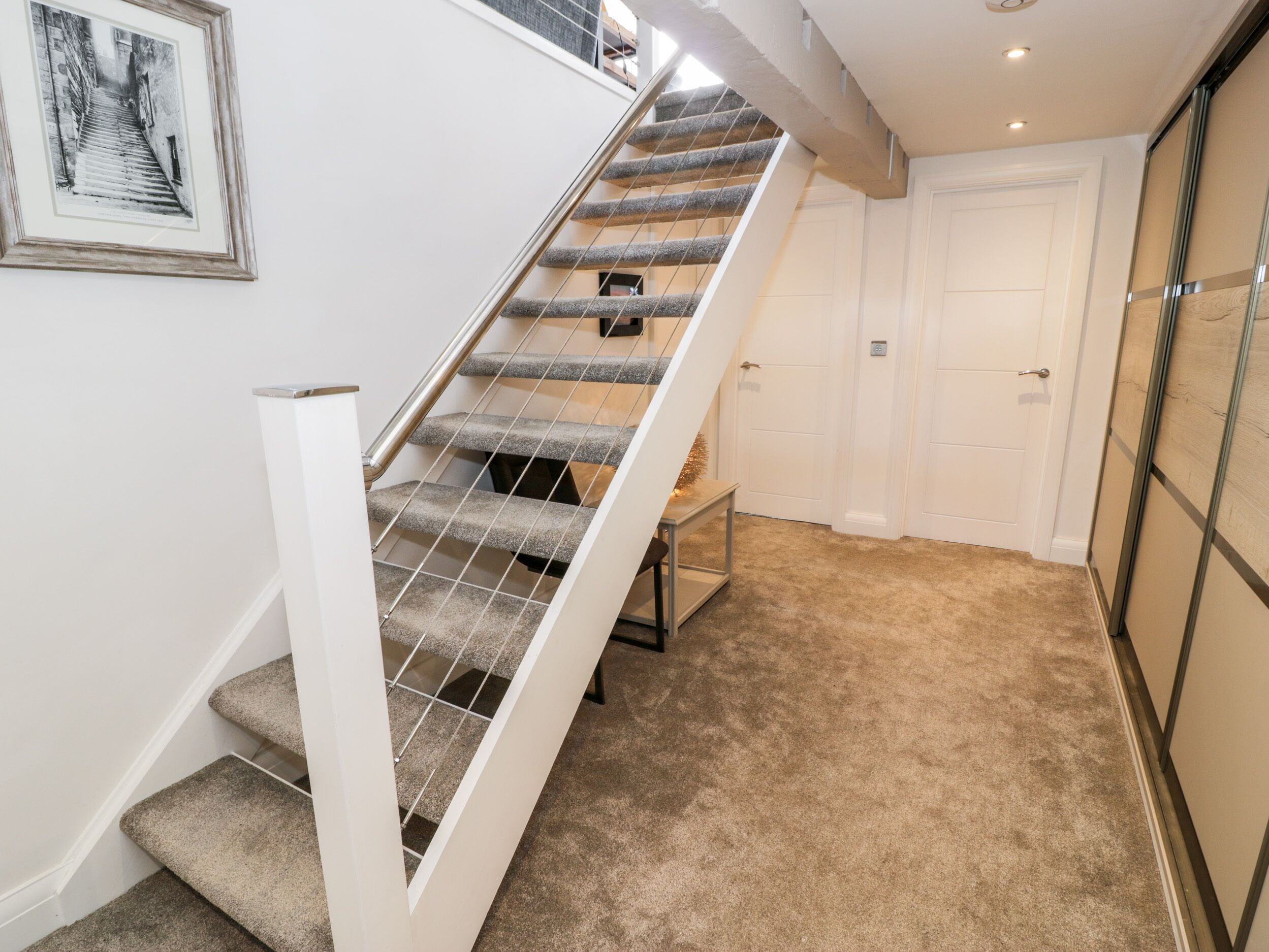 A staircase with a metal railing, carpeted steps, and a door with a light switch.