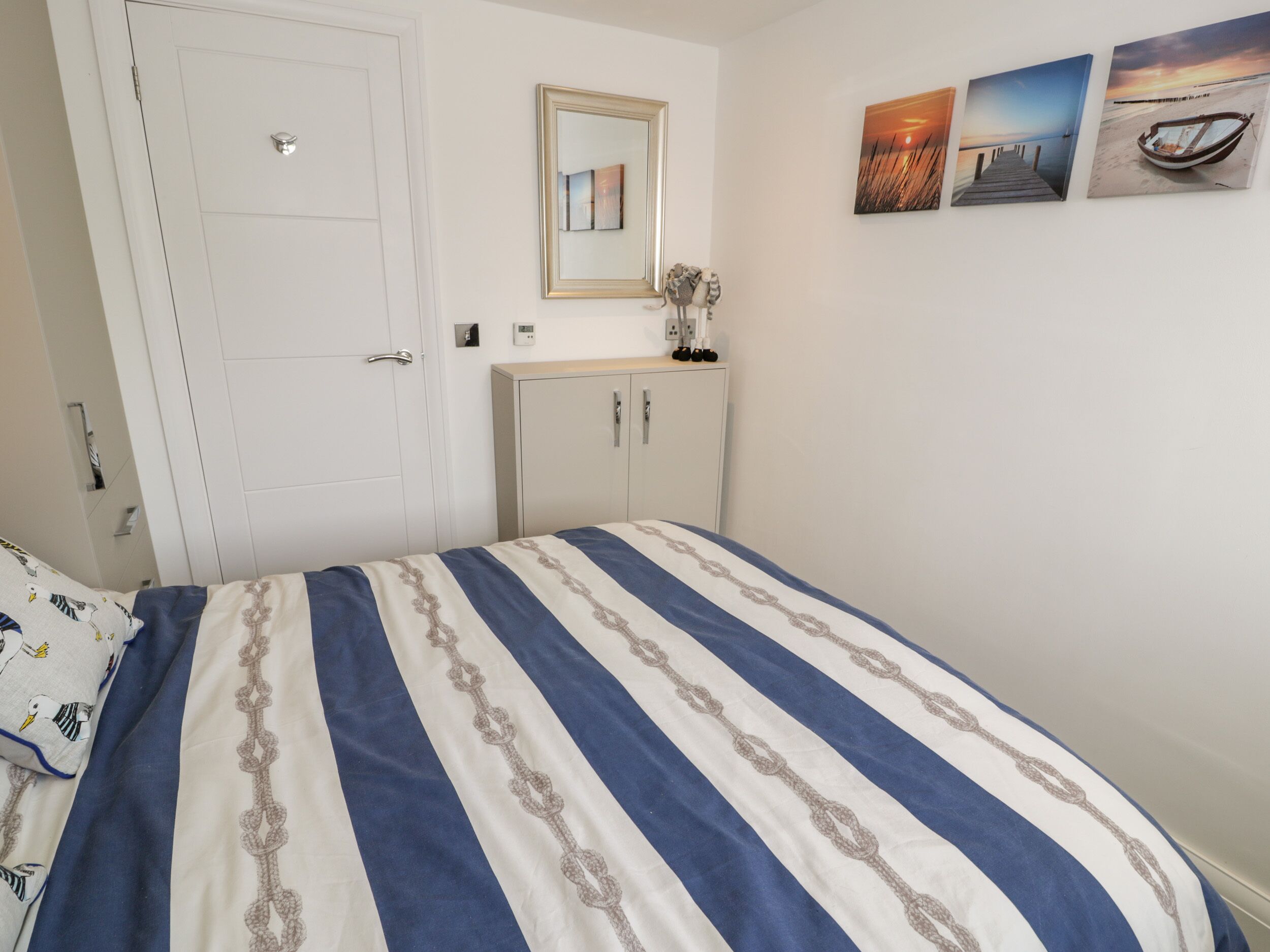 A bedroom with a bed, a wardrobe, a mirror, and wall art.