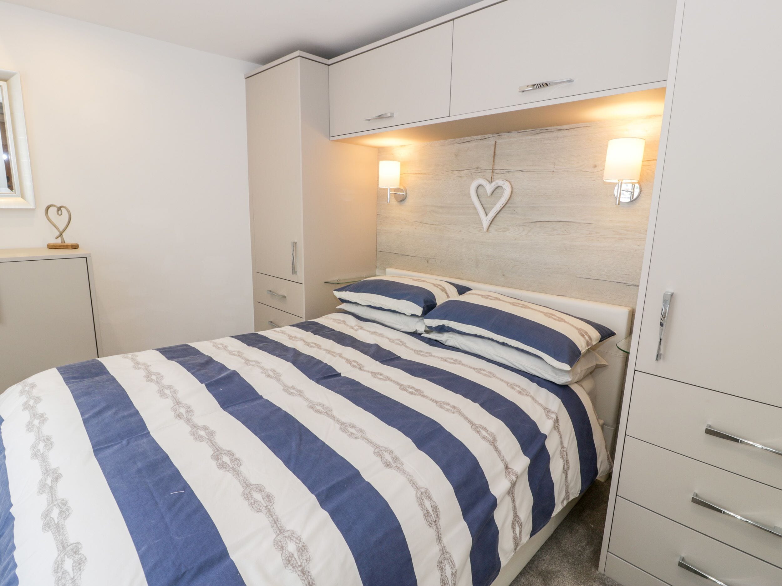 A bedroom with a bed, a wardrobe, and two wall-mounted lights.