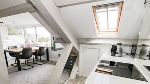 A modern kitchen with a skylight, a dining area with a table and chairs, and a view of the outdoors. - The Sail Loft (Porthmadog)