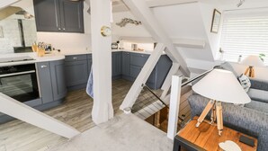 A modern loft with a kitchen, dining area, and living space. - The Sail Loft (Porthmadog)