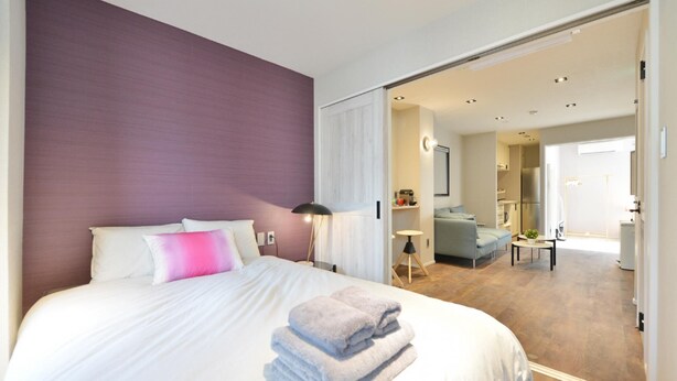 A hotel room with a large bed, a desk, and a view into the living area. - Real Life Meguro River Superb 2BR 6pax Shibuya (Tokyo)