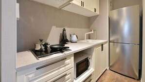 A compact kitchen with a stainless steel refrigerator, a microwave, a stove, and a kettle. - Real Life Meguro River Superb 2BR 6pax Shibuya (Tokyo)