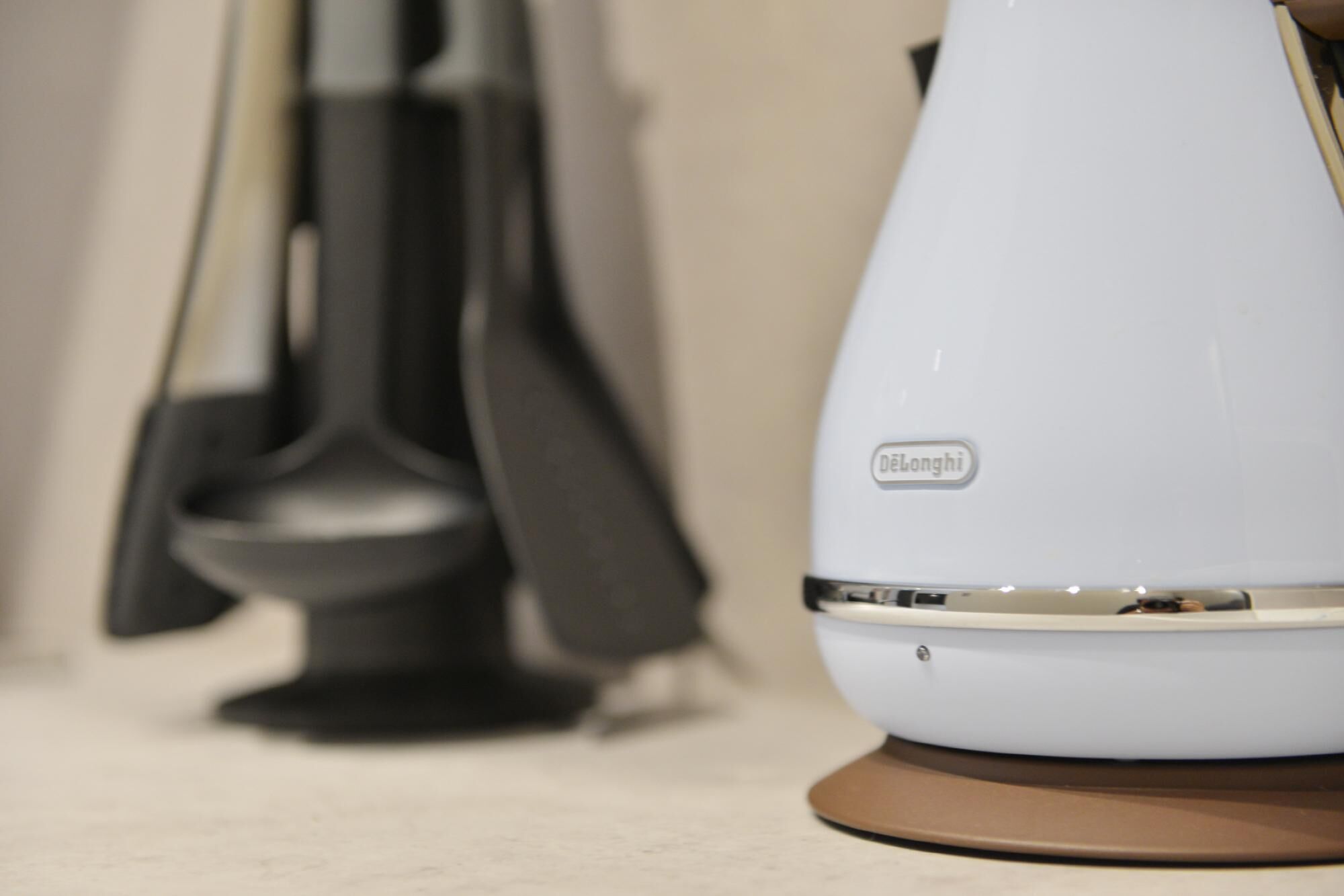 Un bollitore elettrico bianco con base marrone ed etichetta con su scritto "DeLonghi".