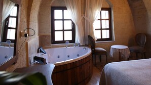 A room with a large bathtub, two chairs, a small table, and a bed. - Karma Cappadocia (Nevsehir)