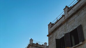 A historic stone building with multiple windows and a sign indicating it is a hotel. - Karma Cappadocia (Nevsehir)
