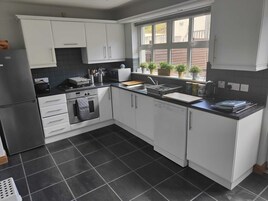 Una cocina moderna con armarios blancos, un salpicadero de azulejos negros y un ventanal con vistas a un jardín.