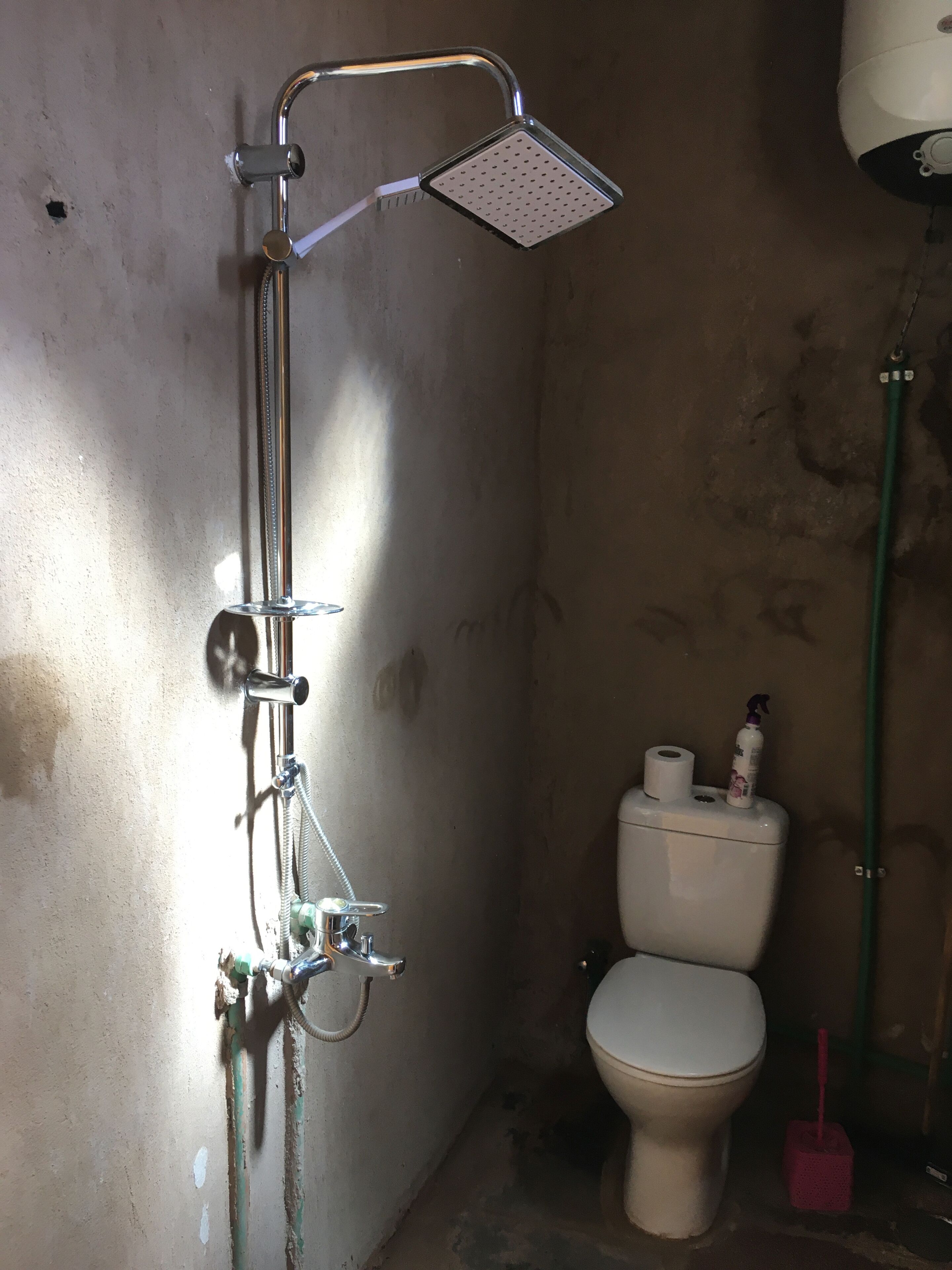 Une salle de bain équipée d’une douche, de toilettes et de produits de nettoyage.