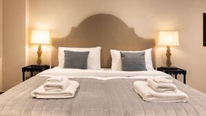Una habitación de hotel con una cama grande, dos mesitas de noche con lámparas y un cabecero.