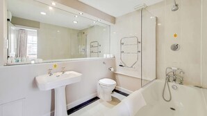 Ein modernes Badezimmer mit Waschbecken, Toilette und Badewanne, alles in Weiß.