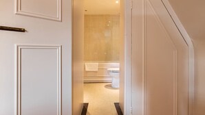 Ein Flur, der zu einem Badezimmer mit Toilette und Badewanne führt.