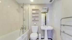 Uma casa de banho moderna com banheira, sanita e lavatório.