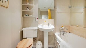 Uma casa de banho compacta com sanita, lavatório e banheira.