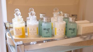 Uma prateleira no banheiro com diversos produtos de higiene pessoal, incluindo condicionador e loção corporal Quercus.