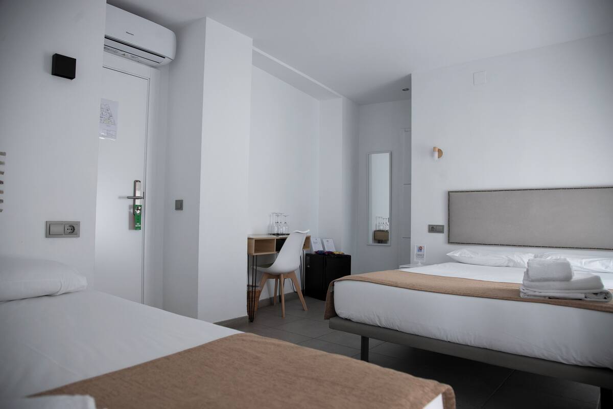 Een hotelkamer met twee bedden, een bureau, een stoel en een grote spiegel.