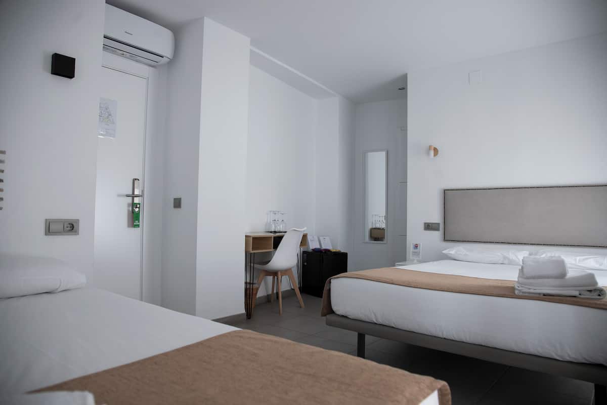 Une chambre d’hôtel avec deux lits, un bureau, une chaise et un grand miroir.